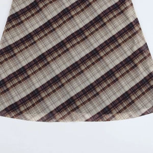 Detailansicht des Saums an einem braun karierten Netzkleid mit feiner Texturierung