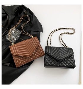 Detail of V-shaped quilted chain shoulder bags in black and brown leather with metal straps