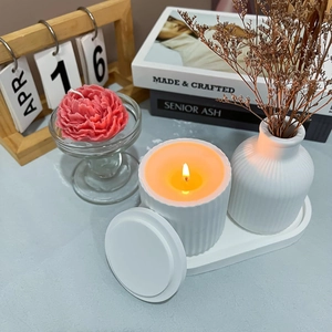 Close-up of white ceramic aromatherapy set with striped candle jar and oval storage tray