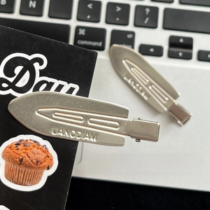 Detail of silver metal hair clips with UANODIAM engraving on a modern keyboard background
