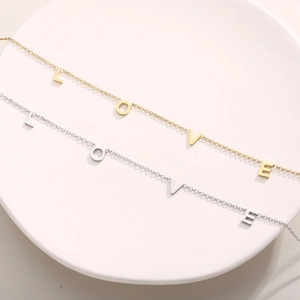 Détail à plat des colliers avec pendentif LOVE doré et argenté sur une assiette blanche