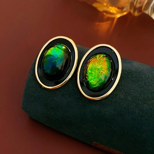 Détail de boucles d'oreilles dorées ovales vintage avec résine verte et pierre opale