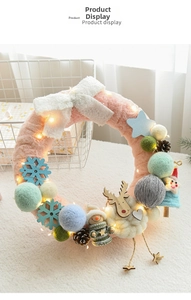 Detail of pink faux fur Christmas wreath with elk decor and warm LED string lights