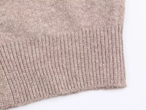Detail shot of oatmeal knit fabric texture and ribbed hem on a button cardigan