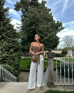 Detail shot of leopard print halter top paired with white wide-leg trousers and brown bag