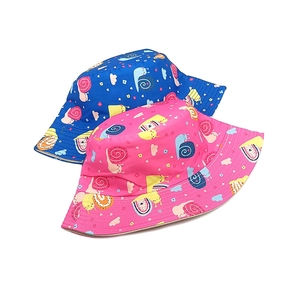 Détail de bobs en coton bleu et rose avec des motifs colorés d'escargots et de nuages