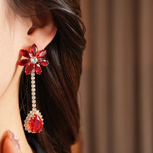 Detailed view of long flower drop earrings with red crystals and gold finish
