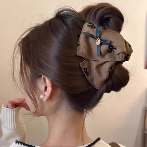 Back view of brown fabric hair claw with black bows on a stylish updo hairstyle