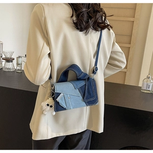 Détail du sac bandoulière en denim patchwork avec breloque peluche porté par un mannequin