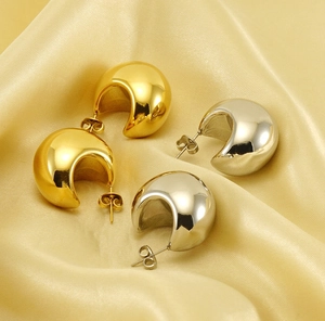 Detailed view of gold and silver teardrop earrings on elegant gold silk fabric