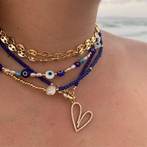 Detail of four-layered gold chain necklace with evil eye beads and natural pearls