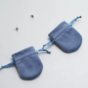 Close-up of blue velvet drawstring jewelry pouches with silk ribbons and round base