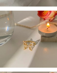 Close-up of golden butterfly ring with white zircons on a white aesthetic background