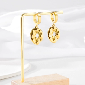 Artistic gold flower earrings with wave texture hanging on a display stand