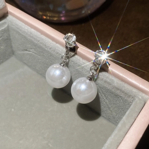Macro view of silver pearl earrings with sparkling zircon studs in a plush jewelry box