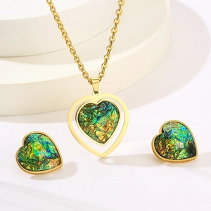 Macro shot of gold-plated heart pendant and earrings set with green iridescent resin inlay