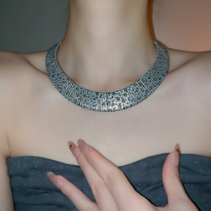 Macro shot of silver metal choker with leopard print cutouts and brushed texture finish
