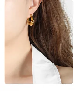 Close-up of golden hollow geometric hoop earrings with intricate mesh weaving texture