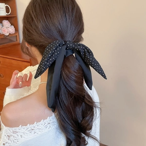 Close-up of a French vintage black polka dot chiffon hair ribbon tied on a ponytail