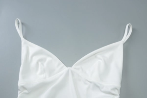 Detail eines weiß gerippten Strickoberteils mit V-Ausschnitt und schmalen Trägern