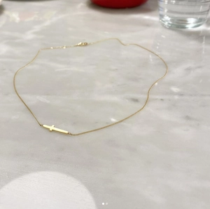 Detail of a gold-plated 925 silver cross pendant necklace on a white marble surface