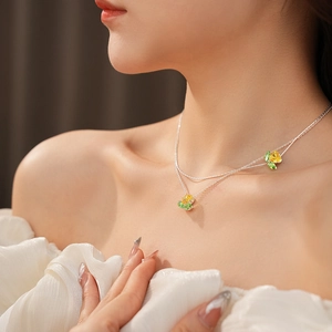 Detailaufnahme einer zweilagigen Silberkette mit gelbem Blumenanhänger an einem Modell