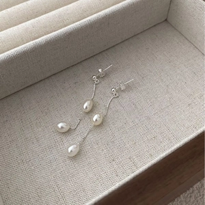Close-up of S925 silver dangling earrings with freshwater pearls and tassels