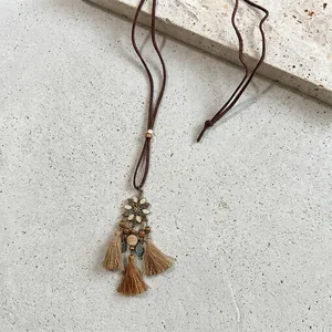 Detail of vintage bohemian necklace with blue enamel flower pendant and wood bead tassels
