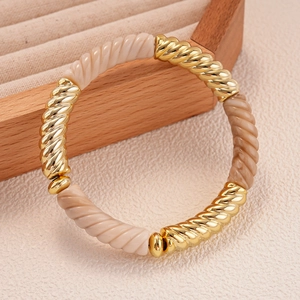 Détail de maillons dorés torsadés et perles en résine marbrée sur un bracelet