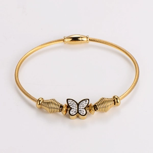 Macro shot of gold butterfly bracelet with white zircon inlay and woven cable texture