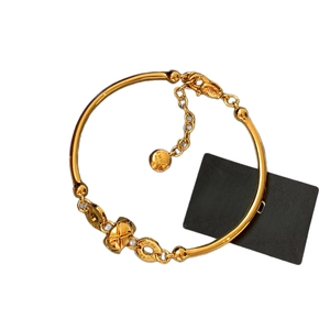 18K gold-plated bamboo bracelet with pearl and circular brand logo charm on white background