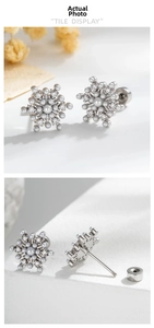 Detail of snowflake cartilage stud earrings with pearls and zircon on white rock background