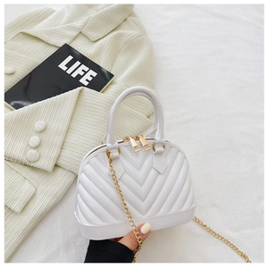 Detail view of a white shell jelly bag with V-shaped texture and gold chain on lifestyle background