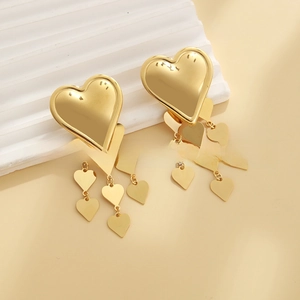 Detailed macro shot of 18k gold heart-shaped tassel earrings on white display board