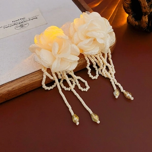 Close-up of cream fabric flower earrings with beaded tassels and crystal drops