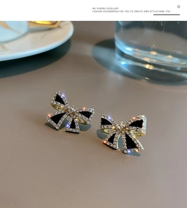 Macro shot of s925 gold bow earrings with black enamel and sparkling rhinestones