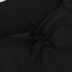 Detail of the V-neckline featuring a velvet bow and elegant gathered pleats on the black dress
