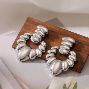Minimalist irregular heart-shaped silver earrings on dark wood with soft background