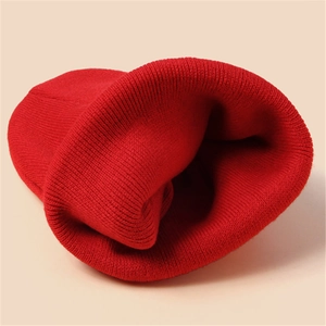 Close-up of vibrant red knitted beanie showing thick ribbed texture and warm yarn detail