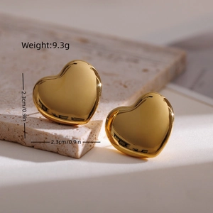 Detail view of heart-shaped gold earrings on stone base with precise size dimensions
