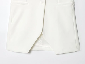 Gros plan sur l'ourlet asymétrique d'un blazer et détails du boutonnage simple