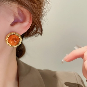 Close-up of vintage golden quilted earring with amber resin stone on model ear