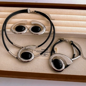 Detailed shot of oval black gemstone jewelry set with spiral silver charms in a display box