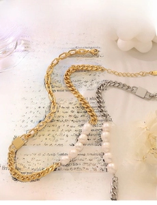 Detail of chunky gold and silver chain necklace with freshwater pearls on a lifestyle backdrop