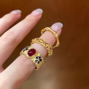 Macro detail of vintage gold bamboo-style ring with red gemstone and enamel floral accents