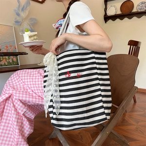 Detailed shot of large striped canvas tote with red embroidery and white lace ribbon