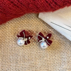 Detail of burgundy velvet bow earrings with white pearl pendants and crystal accents