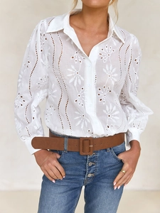 Detailed view of white lace hollow-out design and floral patterns on women's blouse