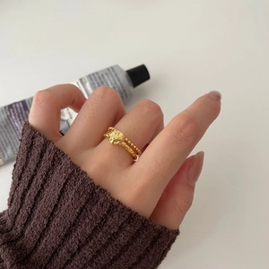 Detail of gold bull head ring with hammered metal texture and beaded silver chain band