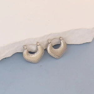 Detail of silver oval hoop earrings with textured finish and lever back closure